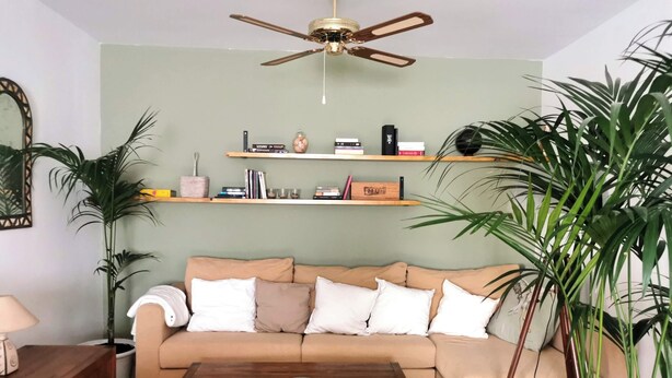 Ein Wohnzimmer mit einem beigefarbenen Sofa, einem Holztisch und Regalen mit Büchern und Dekoration.