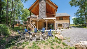 Eine Lodge mit einem Steinkamin, Holzfassade und einer überdachten Veranda mit Sitzgelegenheiten.