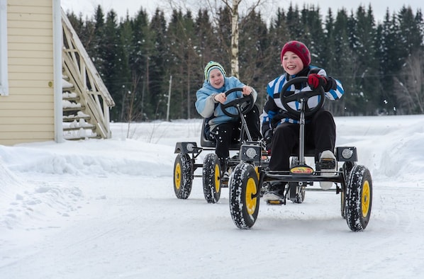 Two people in winter clothing driving a snowmobile on a snowy path. - Spa Hotel Runnin Kartanohotelli (Iisalmi)