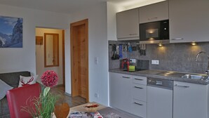 Une cuisine moderne avec des meubles gris, un four à micro-ondes encastré et un évier.