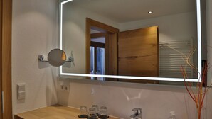 Une salle de bain moderne avec un meuble-lavabo en bois, un grand miroir et un lavabo blanc.