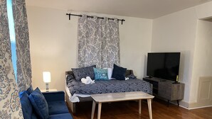 A living room with a sofa, a coffee table, a TV, and patterned curtains. - #1* 5min walk to the Beach, Amazing Virginia Pro Host. (Norfolk)