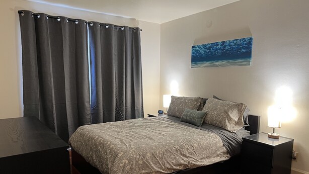A bedroom with a bed, two bedside tables, a nightstand, a window with curtains, and a wall-mounted picture. - #1* 5min walk to the Beach, Amazing Virginia Pro Host. (Norfolk)
