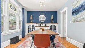 Uma sala de jantar com uma mesa de madeira, cadeiras e um tapete estampado.
