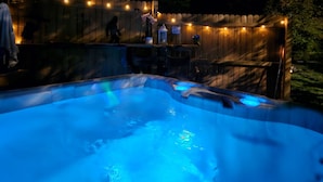 A hot tub with a wooden deck and string lights. - Bigfoot Inn -cabin with loft -near Illinois River (Tahlequah)