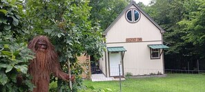 Ein kleines Gebäude mit der Aufschrift "Bigfoot Inn", schlicht und rustikal im Design, umgeben von üppigem Grün.