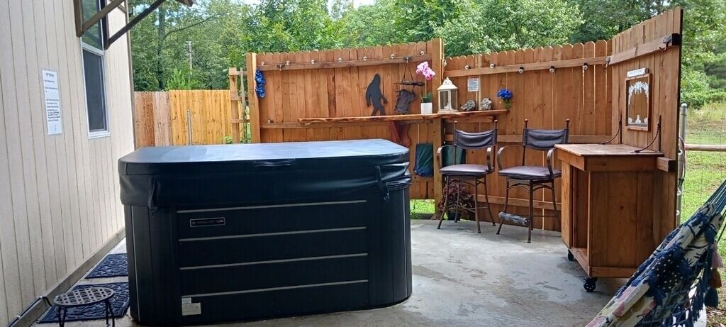 A backyard with a hot tub, wooden deck, and outdoor seating area.