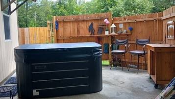 A backyard with a hot tub, wooden deck, and outdoor seating area.