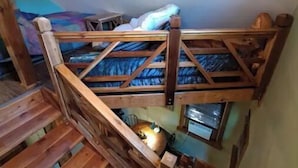A bunk bed with a wooden ladder, a small table, and a hanging light fixture. - Bigfoot Inn -cabin with loft -near Illinois River (Tahlequah)