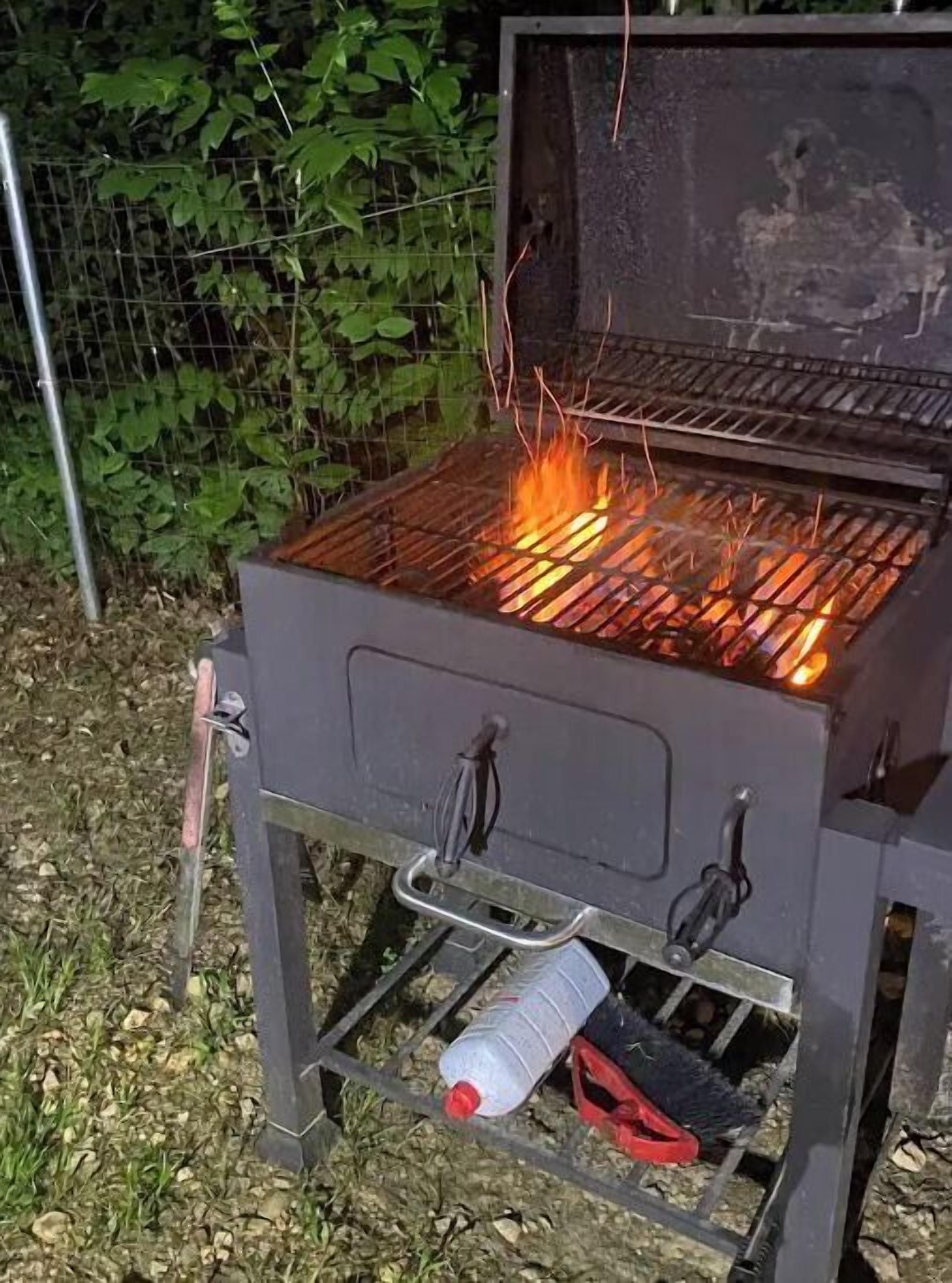 A portable grill with a metal grate and a fire burning on it.