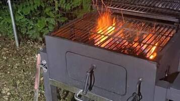 A portable grill with a metal grate and a fire burning on it.