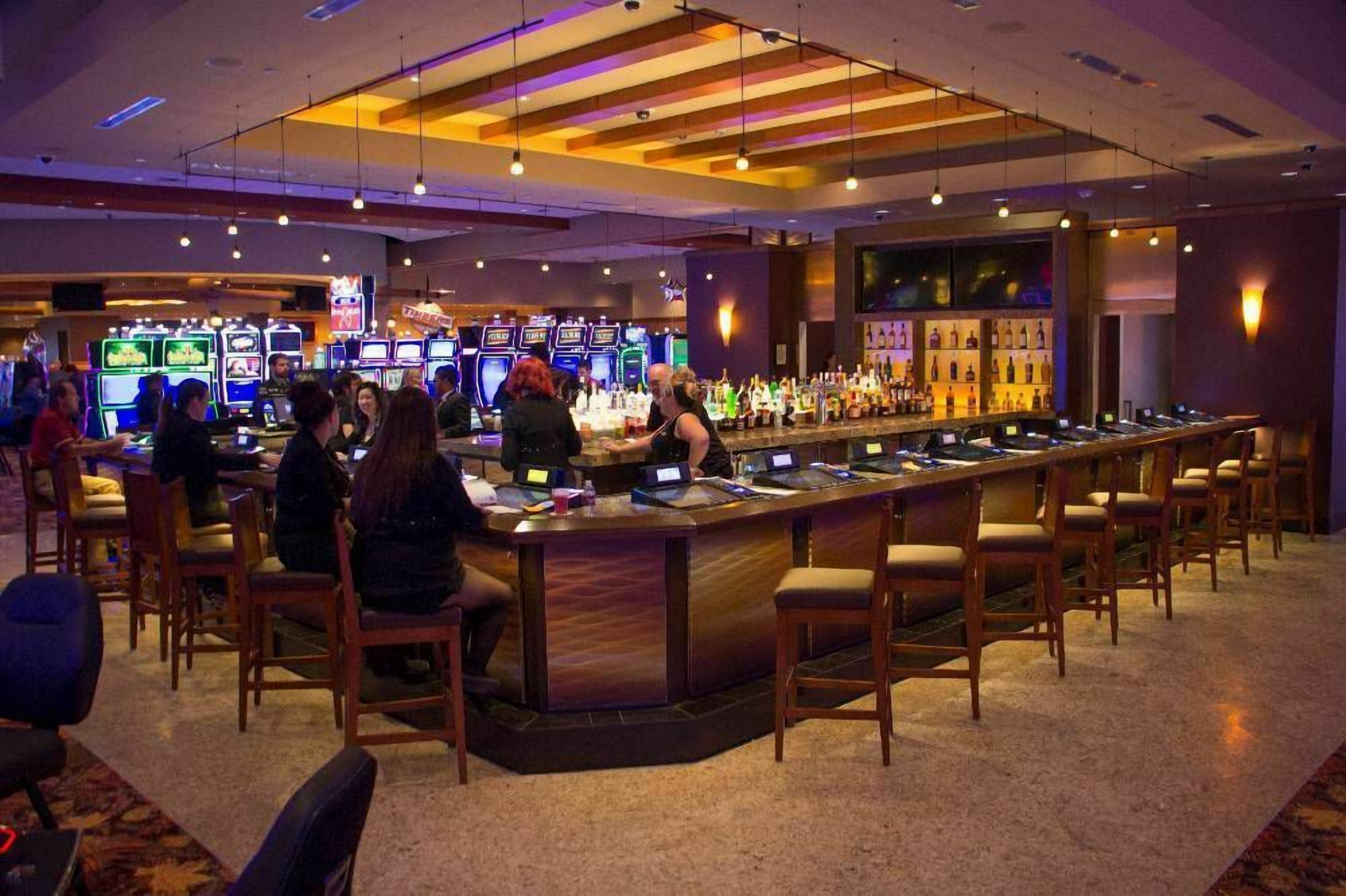 Zona de bar con varias máquinas de juego y una barra con taburetes.