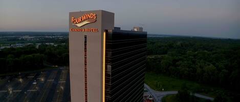 A tall building with a sign reading "Four Winds Casino & Hotel" and a parking lot with marked spaces.