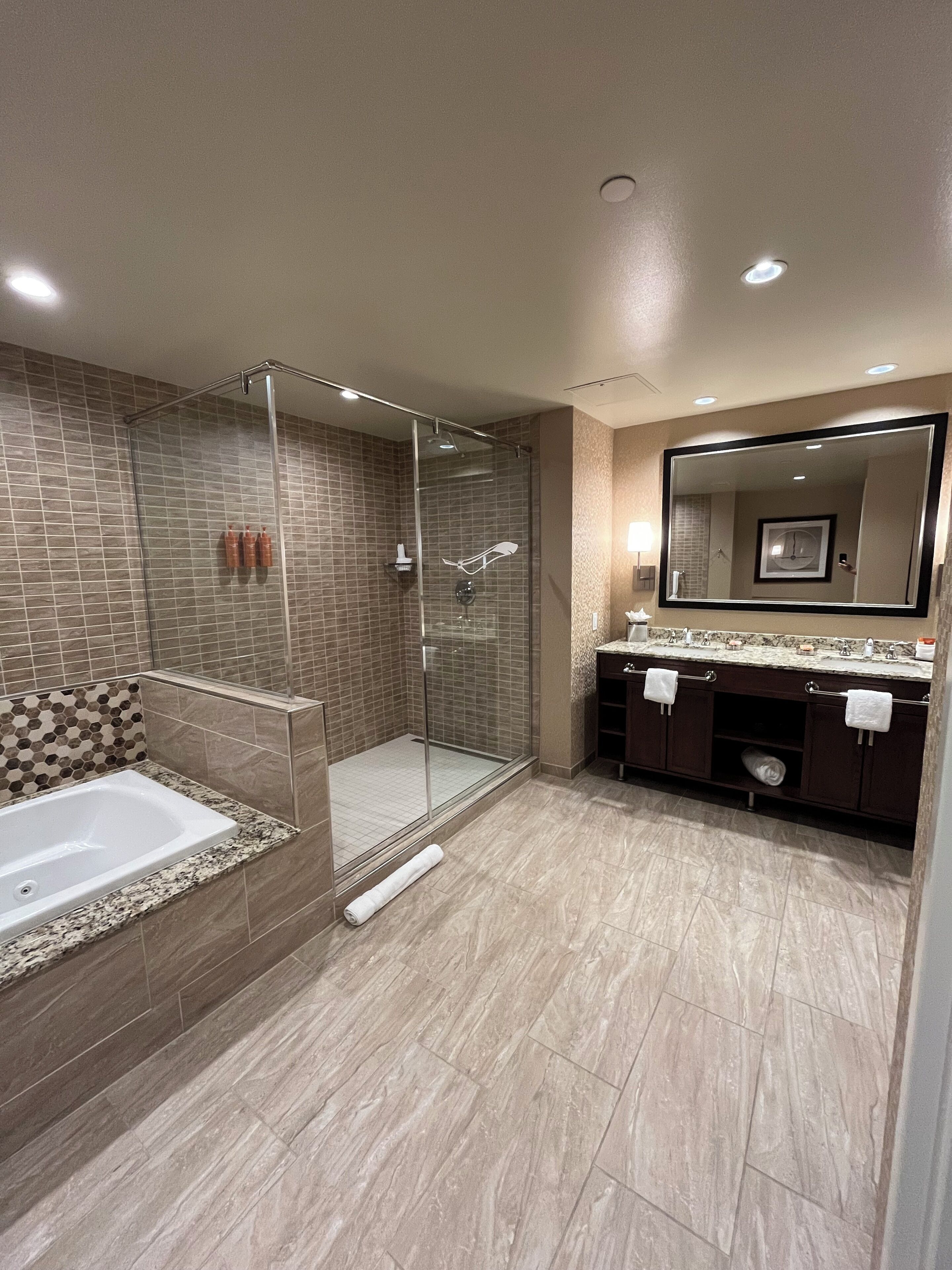 A modern bathroom with a glass-enclosed shower, a freestanding bathtub, and a vanity with a large mirror.