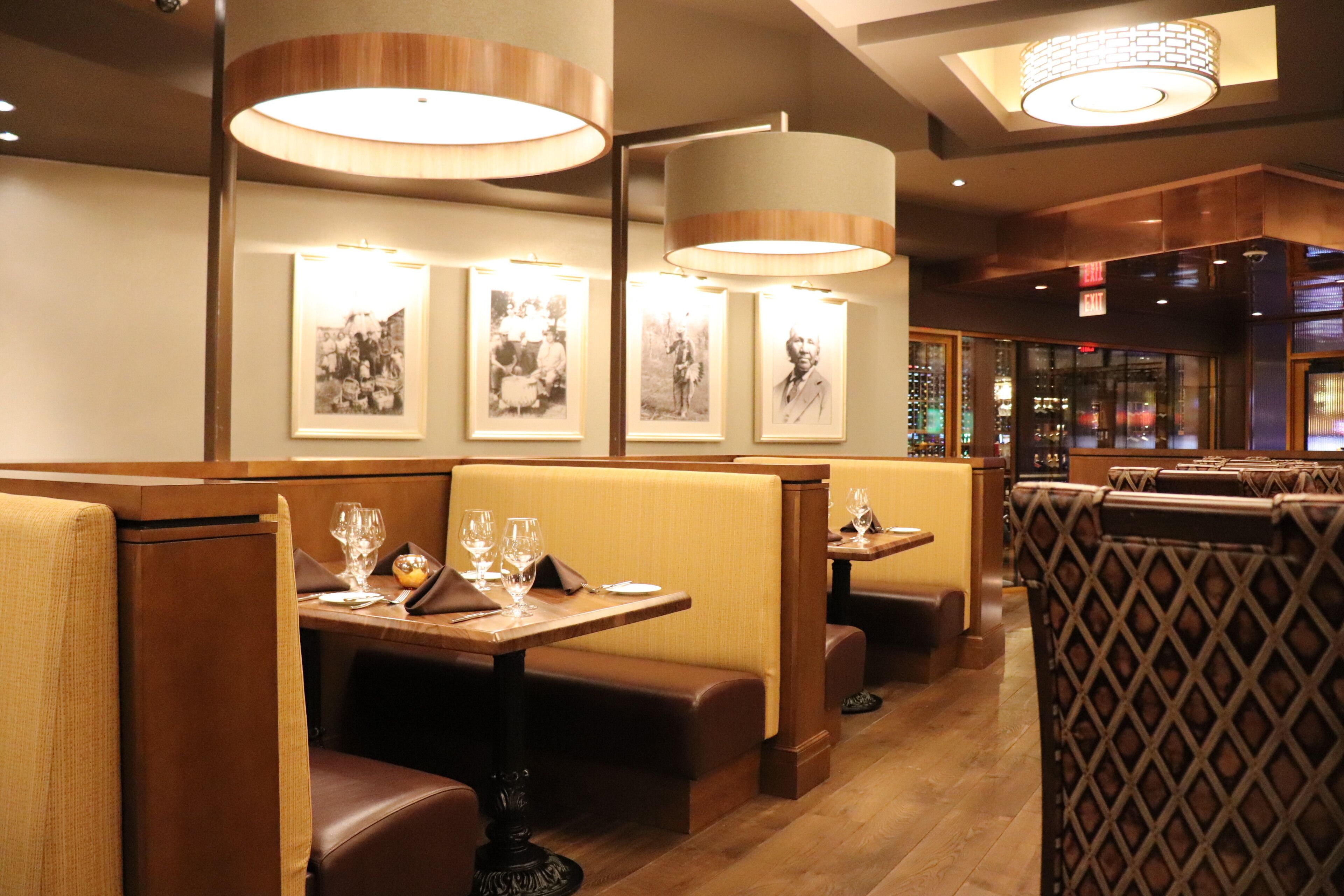A restaurant with booths and tables, wooden flooring, and framed pictures on the wall.