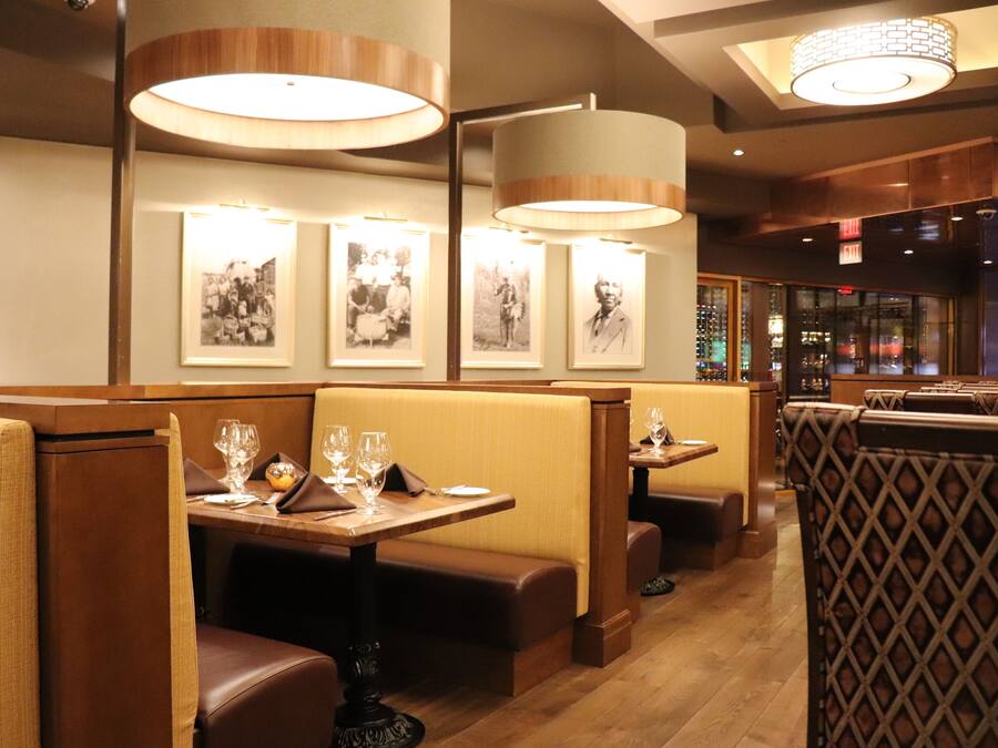 Un restaurante con cabinas y mesas, suelo de madera y cuadros en la pared.