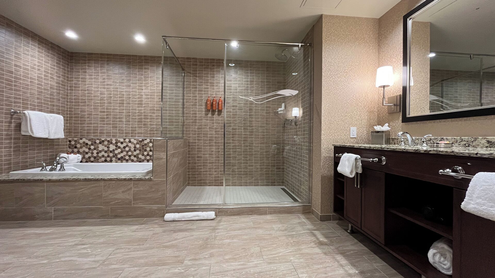A modern bathroom with a glass-enclosed shower, a freestanding bathtub, and a vanity with a mirror.