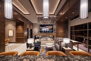 Un hall d’hôtel doté d’un grand écran diffusant des images du « Four Winds Casino – South Bend », d’espaces aménagés avec des sièges et d’une cheminée.