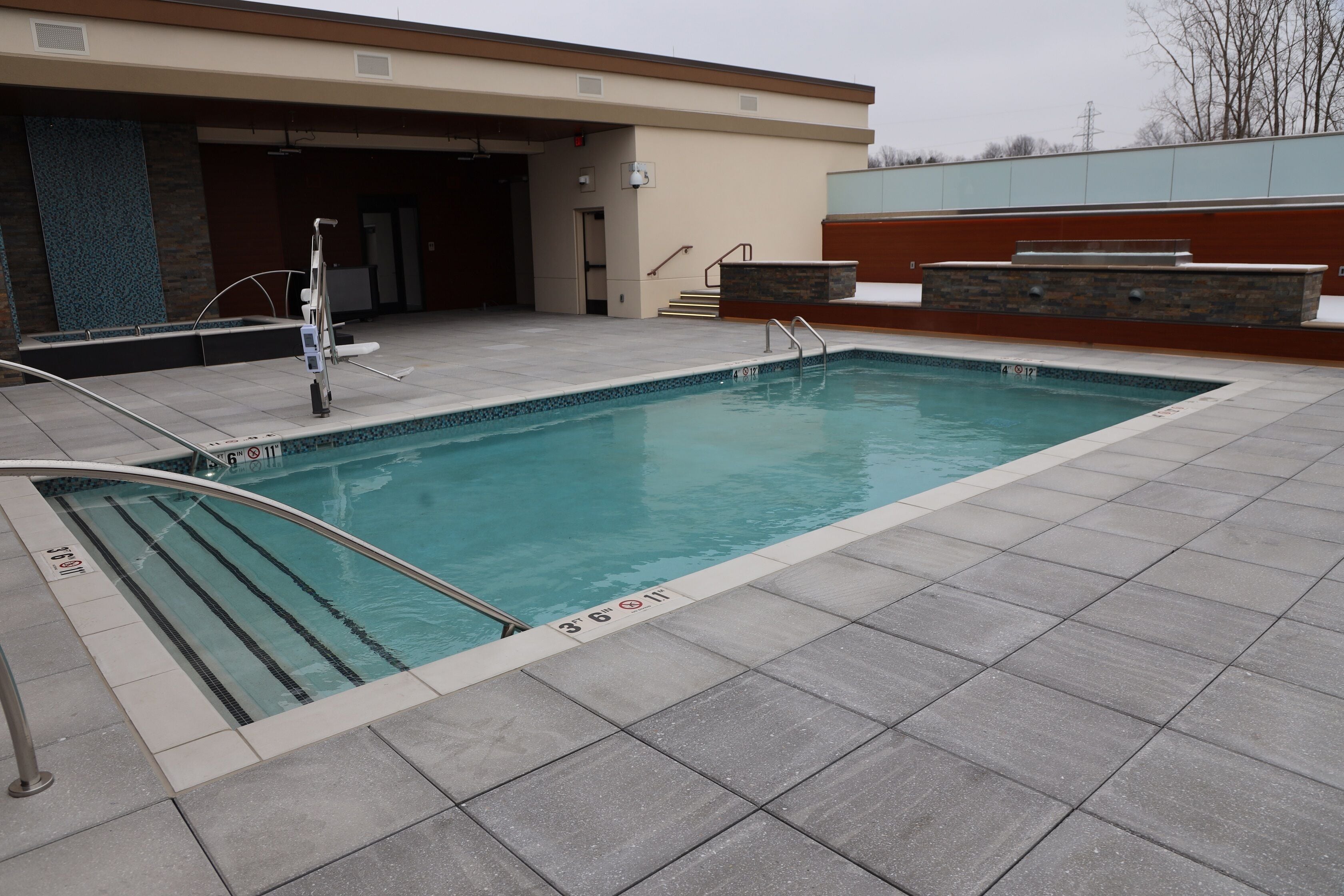 Ein rechteckiger Pool mit deutlichen Bahnen, einer Metallhandstange und einer gefliesten Poolterrasse.