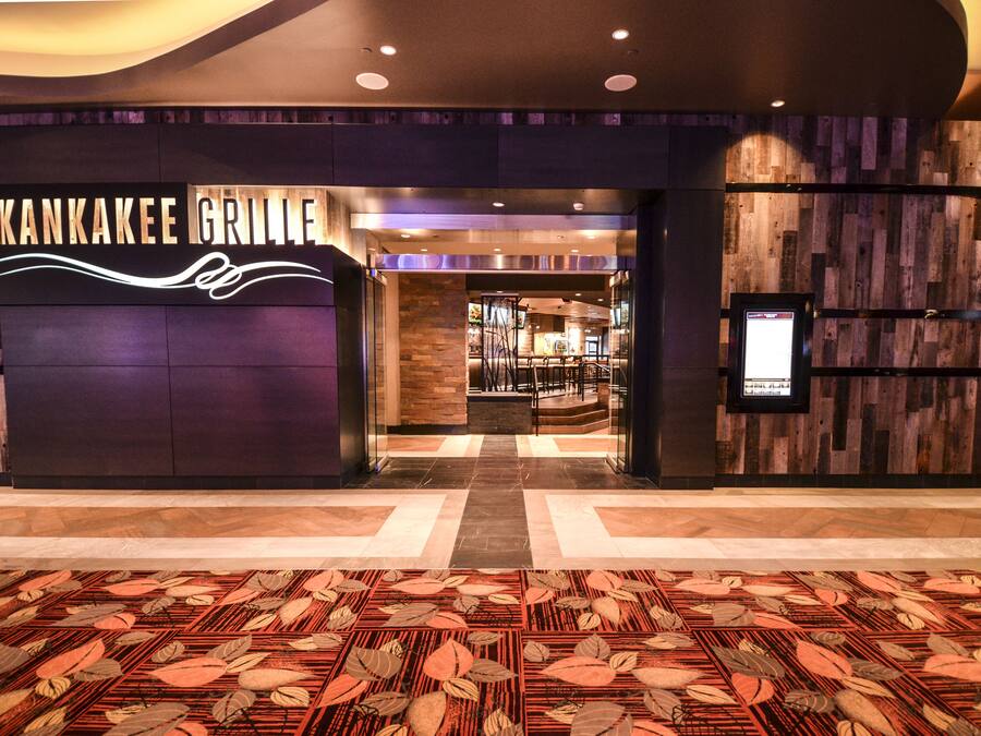 A modern entrance to Kankakee Grille with a checkered floor pattern and a wooden wall backdrop.