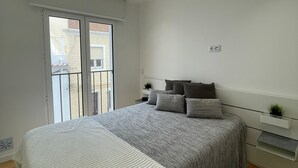 A bedroom with a large bed, a bedside table, a nightstand, and a window with a view of the outside. - Gorgeous 1 BDR (sleeps 4) w/ Ocean View 2 min from the beach (Nazaré)