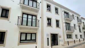 A multi-story building with balconies, a cobblestone street, and a sign indicating the building's address. - Gorgeous 1 BDR (sleeps 4) w/ Ocean View 2 min from the beach (Nazaré)