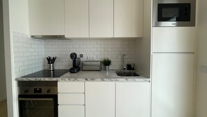 A modern kitchen with white cabinetry, a built-in oven, a microwave, and a toaster. - Gorgeous 1 BDR (sleeps 4) w/ Ocean View 2 min from the beach (Nazaré)