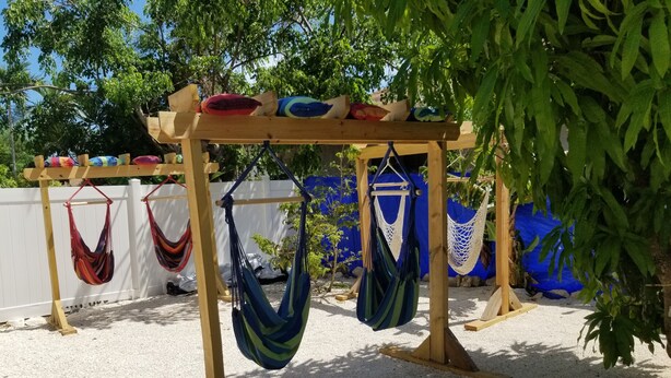 Une pergola en bois agrémentée de plusieurs hamacs et de coussins.