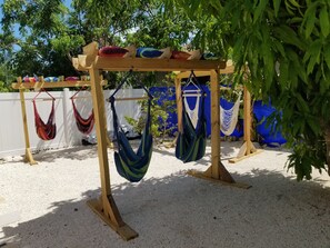 Une pergola en bois agrémentée de plusieurs hamacs et de coussins.