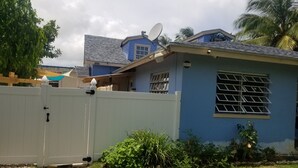 Un quartier résidentiel avec une maison bleue, une clôture blanche et une antenne parabolique.