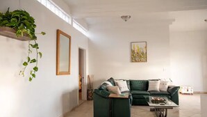 A spacious living room with a green sofa set, a coffee table, and a hanging plant. - Beautiful home in playas de Tijuana (playas de tijuana)