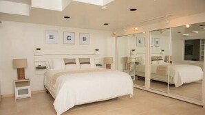 A bedroom with a large bed, bedside tables, a mirror, and framed pictures on the wall. - Beautiful home in playas de Tijuana (playas de tijuana)