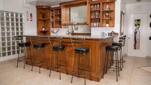 A kitchen with a central island, bar stools, wooden cabinets, and a tiled backsplash. - Beautiful home in playas de Tijuana (playas de tijuana)