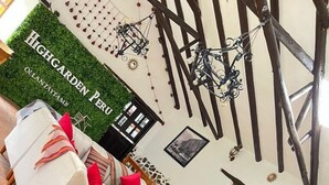 Ein geräumiger Raum mit weißem Sofa, Steinwand und hoher Decke mit freiliegenden Balken.