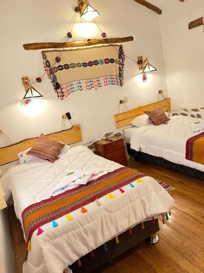 A room with two wooden beds, each with a headboard, a wooden floor, and a wall-mounted light fixture.