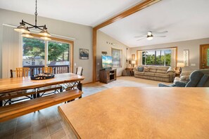 A spacious living area with a dining table, sofas, and a TV.