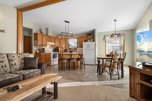 A spacious living area with a sofa, a wooden coffee table, and a TV on a wooden stand.