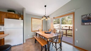 A kitchen with a dining table, chairs, a refrigerator, and a view to the outside. - Cozy Lake Alice Cottage Next to Trails & WI River! Pet Friendly! (Tomahawk)