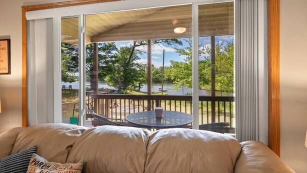 A room with a large sliding glass door leading to an outdoor deck with a table and chairs. - Cozy Lake Alice Cottage Next to Trails & WI River! Pet Friendly! (Tomahawk)