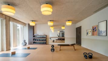 A gym with exercise equipment, a bench, and a mirror.