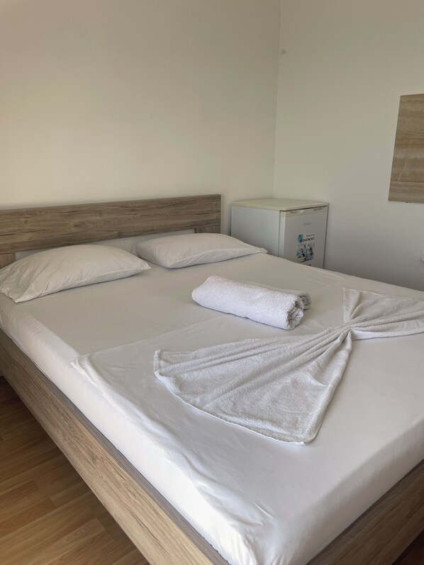 A neatly made bed with white linens and a towel arranged in a knot.