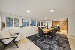 A modern conference room with a long table, multiple chairs, and large windows.