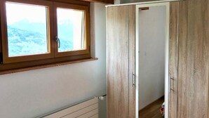 A bedroom with a wooden wardrobe, a radiator, and a window with a view of the outdoors. - Petit Appartement à Louer Dans le Val Dhérens (Vernamiège)