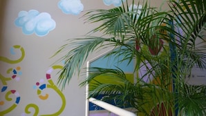 A room with a colorful wall mural, a staircase, and a potted plant. - Ostello Torino (Turin)