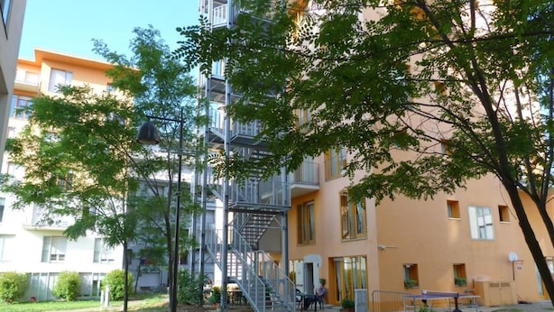 A multi-story building with a fire escape, outdoor seating, and a basketball court. - Ostello Torino (Turin)