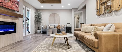 Una sala de estar moderna con televisor de pantalla plana, chimenea, sofá y una mesa de centro.