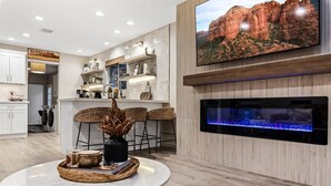 Una sala de estar moderna con un televisor de pantalla plana grande, un acuario y una zona de comedor con una mesa de mármol.