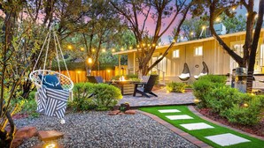 Un área de patio con una silla colgante, un hogar para fogata y mobiliario exterior.