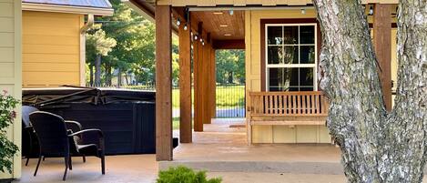 A covered patio area with outdoor furniture, a stone wall, and a view of a residential property.