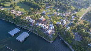 An aerial view of a coastal residential area with houses, a dock, and a golf course.